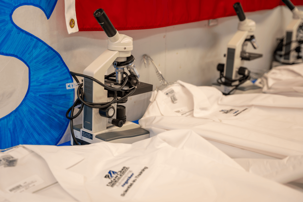 A microscope and white lab coat lay on a table.
