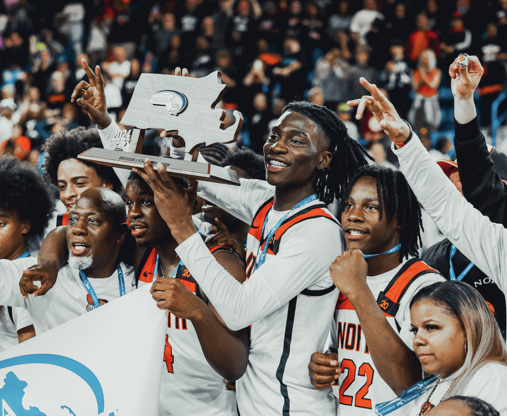 Players cheer and hold a trophy on the basketball court.